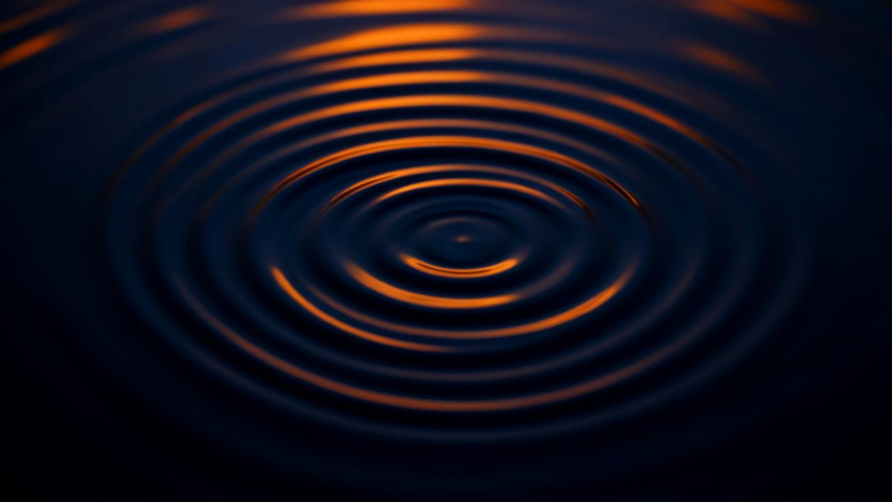 Concentric ripples spreading across still water lit in navy and warm orange tones