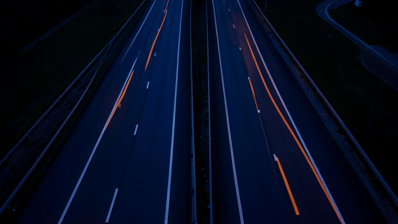 Two roads separated by a divider merging into one lane, in navy and orange tones